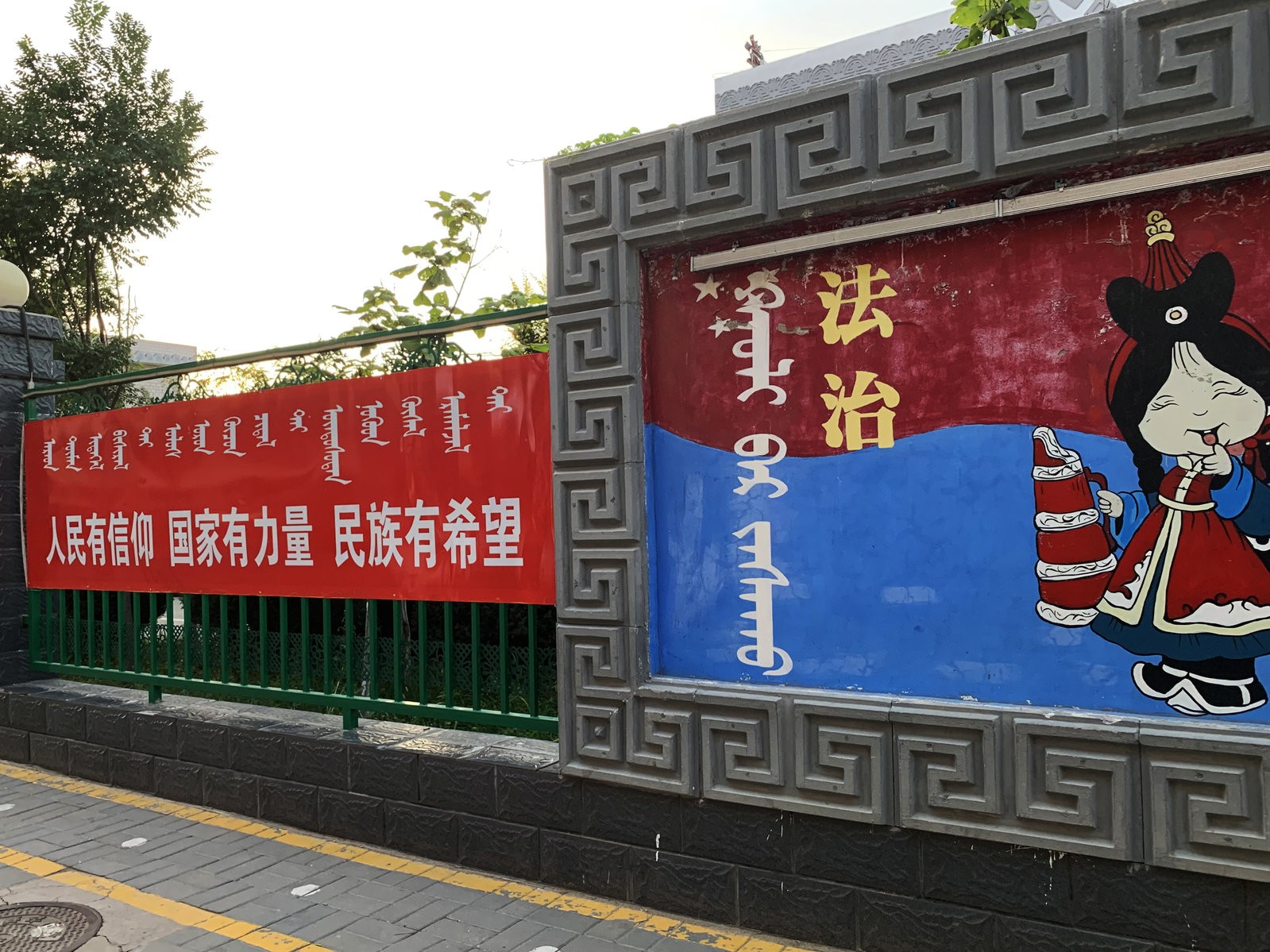 A sign (left) outside a Mongolian-language school in Hohhot, Inner Mongolia, reads: "When the people have conviction, the state has strength and the ethnic minorities have hope." The sign at right says: "Rule of law."